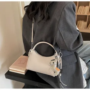 Detailed view of the stylish beige crescent crossbody bag featuring cute horse charm.