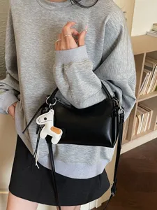 Black crescent shoulder bag for women, stylish underarm bag with cute horse charm.