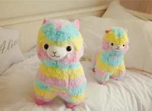Detail shot of lovely colorful rainbow alpaca plush toys displayed on a cozy bedroom bed.