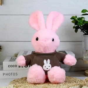 Detailed view of cute pink plush rabbit toy wearing brown knitted sweater with lovely rabbit patch.