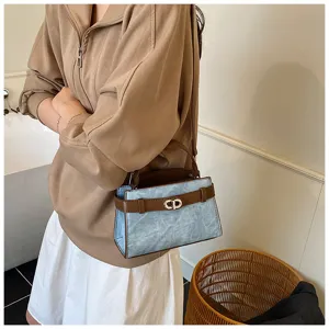 Close-up detail of stylish casual shoulder bag with blue texture and brown belt buckle.