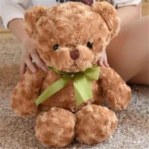 Detailed view of cute brown plush teddy bear, featuring soft curly fabric and green ribbon.