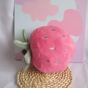 Detailed shot of cute pink strawberry plush toy with green leaves and silver seed embroidery.