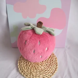 Close-up detail shot of the cute pink strawberry plush toy sitting on a woven mat.