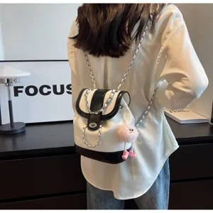 Stijlvolle zwart-witte lederen kettingrugzak voor dames met schattige pluche pop.