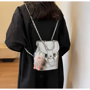 Gedetailleerd overzicht van zilveren metallic rugzak met ketting en schattige pluche hanger.