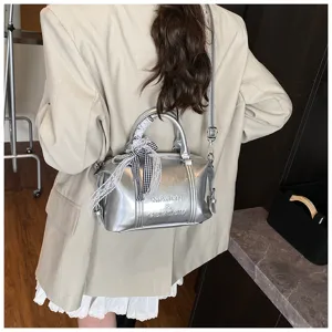 Silver metallic pillow handbag featuring a chic lace bow ribbon detail and shoulder strap.