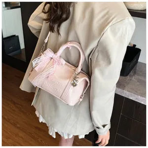 Detailed view of pink patent leather pillow bag with cute lace bow and heart charm pendant.