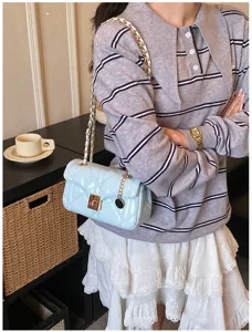 Light blue quilted leather shoulder bag with chic metal chain strap and elegant clasp detail.