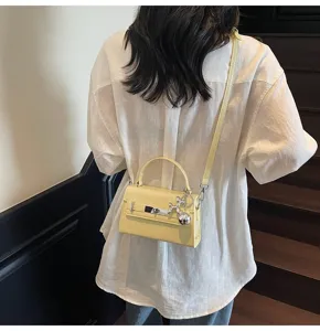Stylish yellow women shoulder crossbody Kelly handbag with metal lock and cute dog charm.