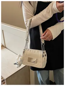 Stylish white patent leather women's shoulder bag with metal chain strap and cute bear charm.