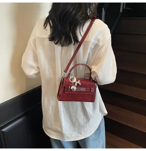 Wine red patent leather Kelly handbag for women, chic crossbody shoulder bag with metal charm.
