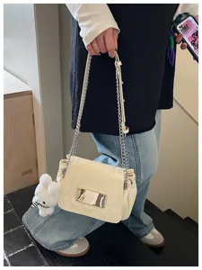 Close-up detail of the elegant cream shoulder bag showing the chain strap and metal clasp.