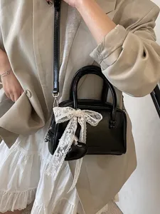 Women black patent leather bowling bag with white lace bow and heart charm crossbody.