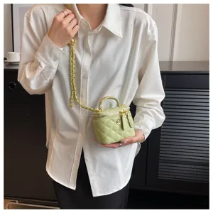 Close-up detail of the light green quilted mini handbag with gold chain strap and chic flower.