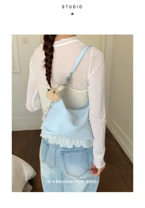Detailed back view of a stylish light blue dumpling shoulder bag with cute plush charm.