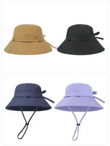 Fashionable wide brim bucket hat with bow detail and adjustable strap for outdoor sun protection.