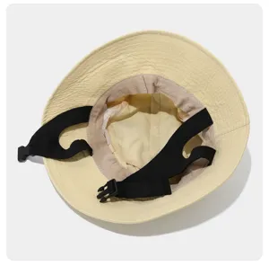 Detailed view of beige outdoor bucket hat with black adjustable chin strap, breathable.