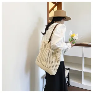 Beige woven tote bag with brown strap, casual hollow-out crochet design for summer resort.