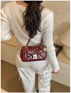 Detail shot of burgundy quilted chain shoulder bag, elegant vintage design with metallic hardware.