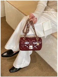 Details of the dark red quilted chain shoulder bag, elegant metallic lock and strap.