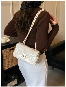 Detailed shot of trendy quilted shoulder bag with chain strap and stylish lock closure.