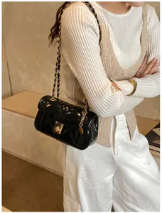 Detailed view of women's black patent quilted chain shoulder bag with chic lock closure.