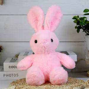 Detail shot of the cute pink plush rabbit toy sitting on a woven mat with cozy room background.