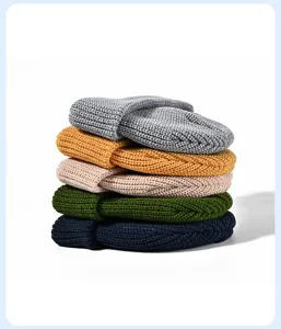Detailed view of a neat stack of colorful knitted beanie hats in gray, yellow, and green.
