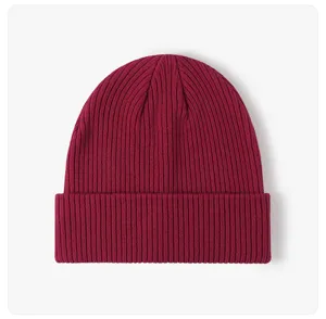 Close-up detail of burgundy ribbed knit beanie fabric texture, winter warm wool cap material