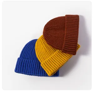 Nahaufnahme Detailansicht von kuscheligen Strickmützen in Blau, Gelb und Braun, warmes Design.