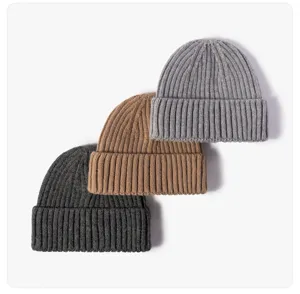 Detailansicht dicker Rippstrickmützen in drei neutralen Farben mit Umschlag.