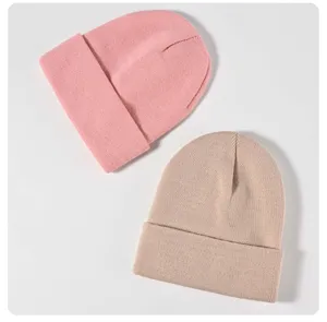 Vista detallada de gorros de punto lisos rosa y kaki, con textura suave y tejido muy cálido.