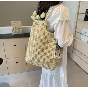 Dettaglio della borsa in paglia intrecciata con capienza e nappine decorative eleganti.