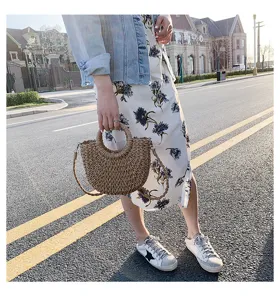 Detailansicht einer stilvollen handgemachten Stroh-Handtasche mit rundem Griff für den Sommer.