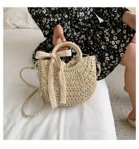 Detailansicht der modischen Strohgewebe Handtasche mit eleganter Schleife und rundem Griff.