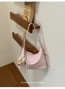 Pink leather shoulder bag detail view, casual dumpling crossbody bag with cute bear charm.