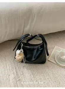 Black hobo shoulder bag detailed view on textured rug with book and teacup lifestyle.