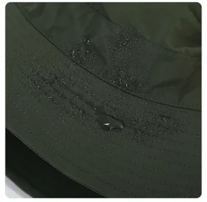 Nahaufnahme Detail des dunkelgrünen wasserdichten Bucket Hats mit wasserabweisendem Stoff.