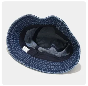 Washed vintage denim bucket hat detail view, showing inner 100% cotton label and neat stitching.