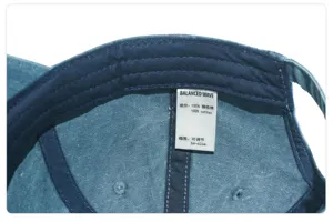 Close-up detail of the inner cotton wash label and adjustable strap on a denim baseball cap.