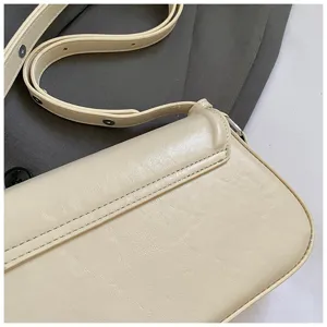 Vue de détail d'un élégant sac à épaule en cuir beige avec bandoulière réglable et détails.