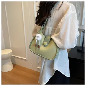 Minimalist green shoulder bag detail, elegant underarm purse with cute fluffy plush charm.