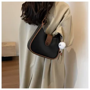 Detailed view of fashionable black and brown crossbody shoulder bag worn by model, chic style.