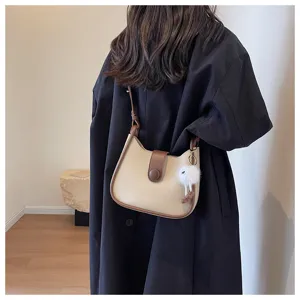 Detailed shot of a chic minimalist beige and brown cross-body shoulder bag for women.