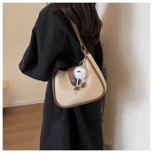Detailed view of the stylish two-tone shoulder bag with cute plush pendant and clean design.