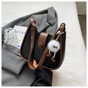 Trendy women's contrast color shoulder crossbody bag with cute fluffy plush monster doll charm.