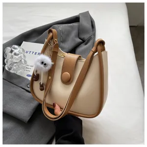 Minimalist contrast shoulder bag for women, stylish bucket handbag with cute plush pendant accessory.