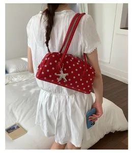 Detailed shot of a sweet red polka dot bowling shoulder bag with a cute metal starfish charm.