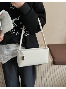 Detailed view of minimalist white baguette shoulder bag, sleek design with metal charm.